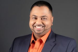 Kenneth Mohabir's Headshot, with Blue Blazer and Orange dress shirt